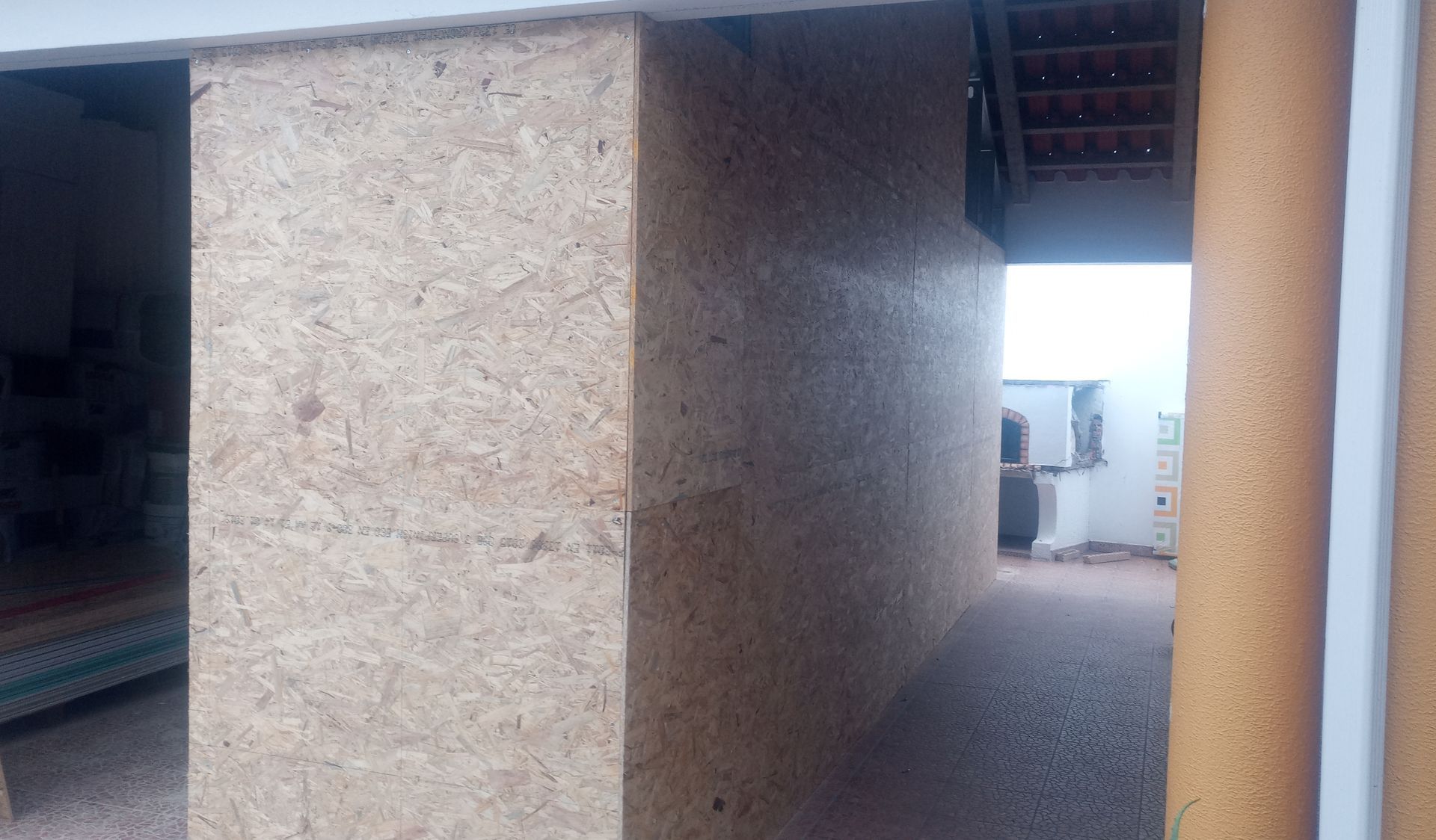 Parede de madeira OSB com vista para um telhado e um aparelho de ar condicionado.