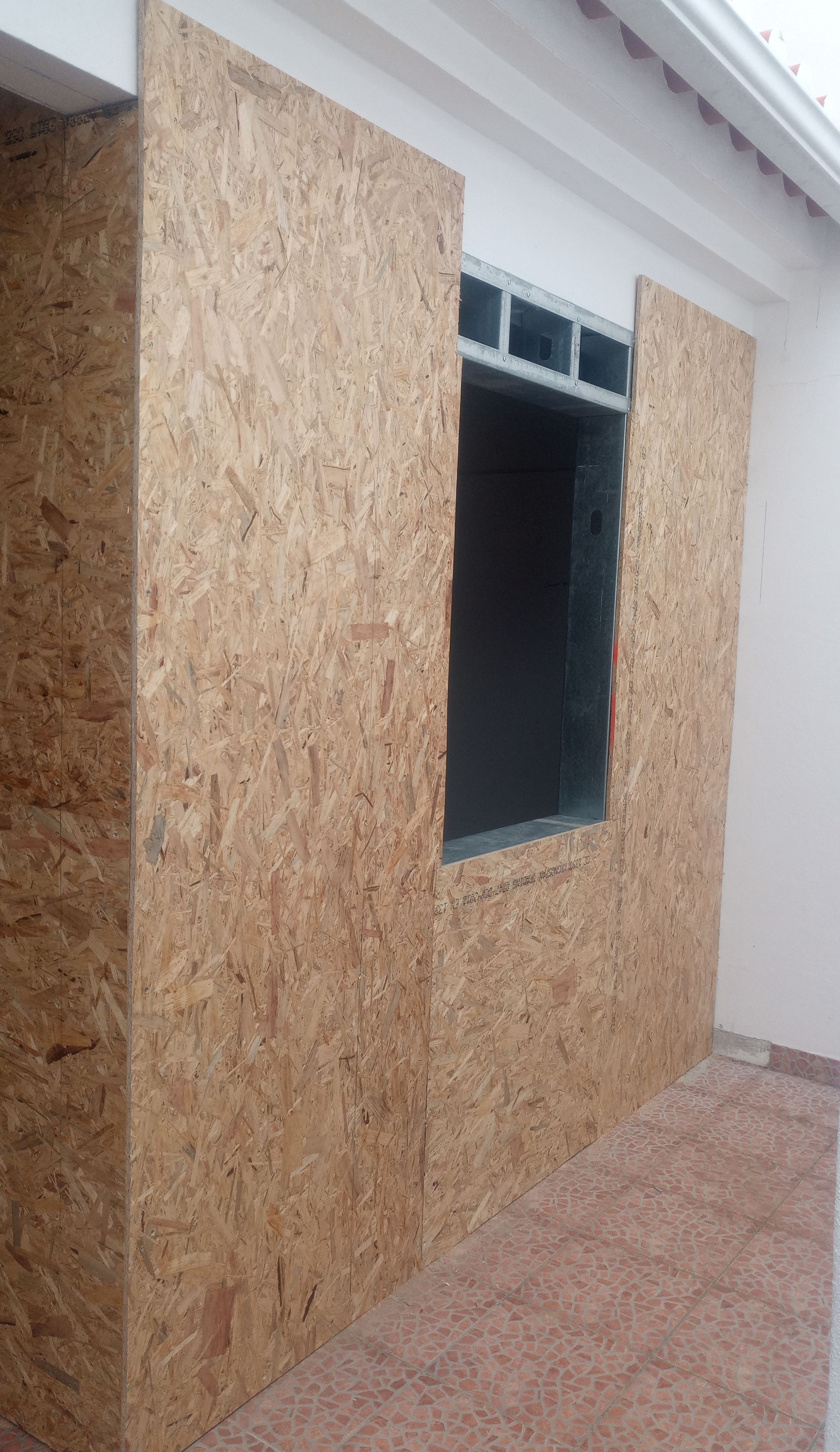 Placas de OSB revestem a parede externa ao redor da abertura de uma janela.