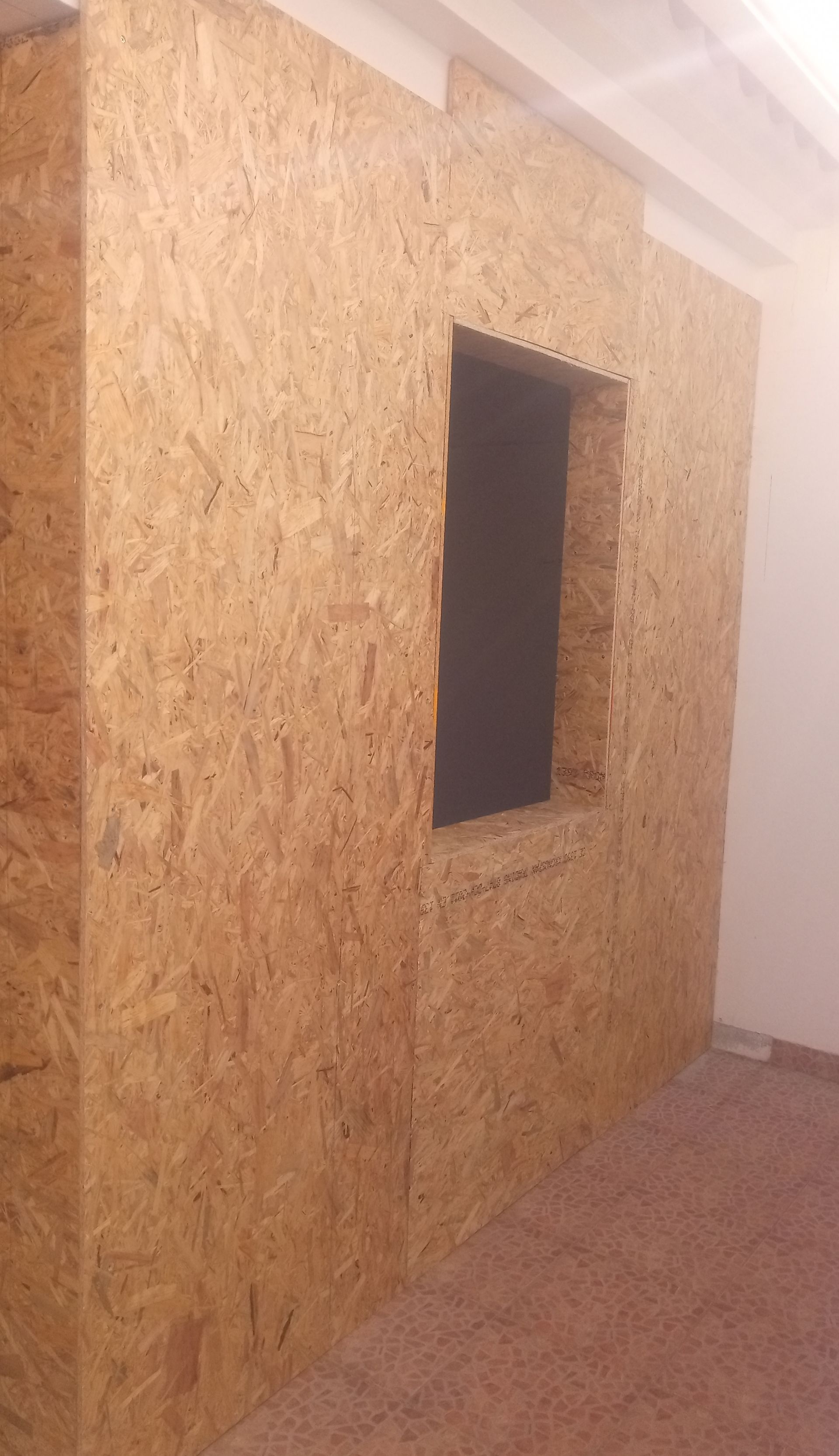 Painéis de parede em OSB com recorte retangular para janela em um cômodo.