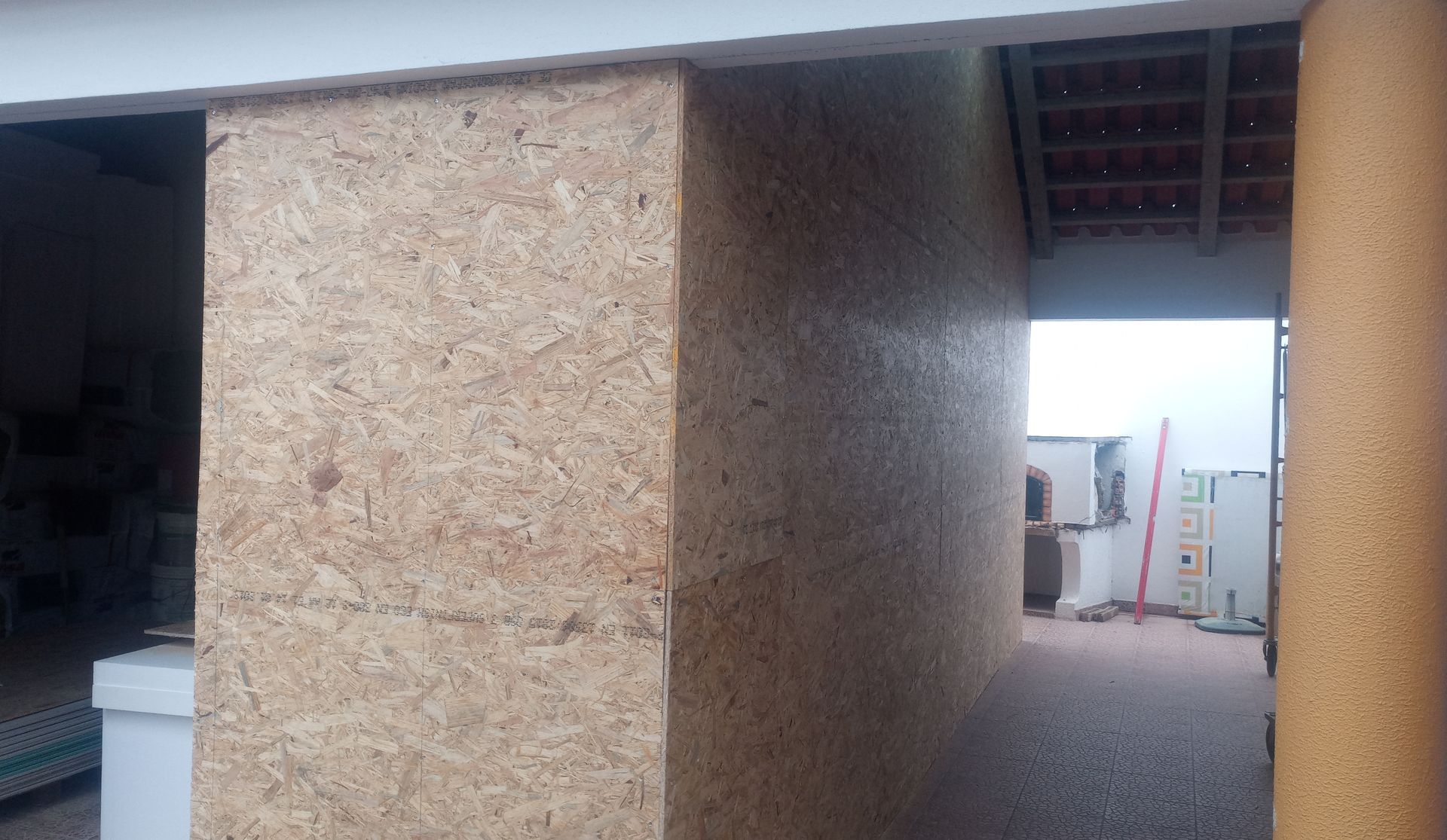 Parede e pilar texturizados em tom bege com abertura para uma área externa.