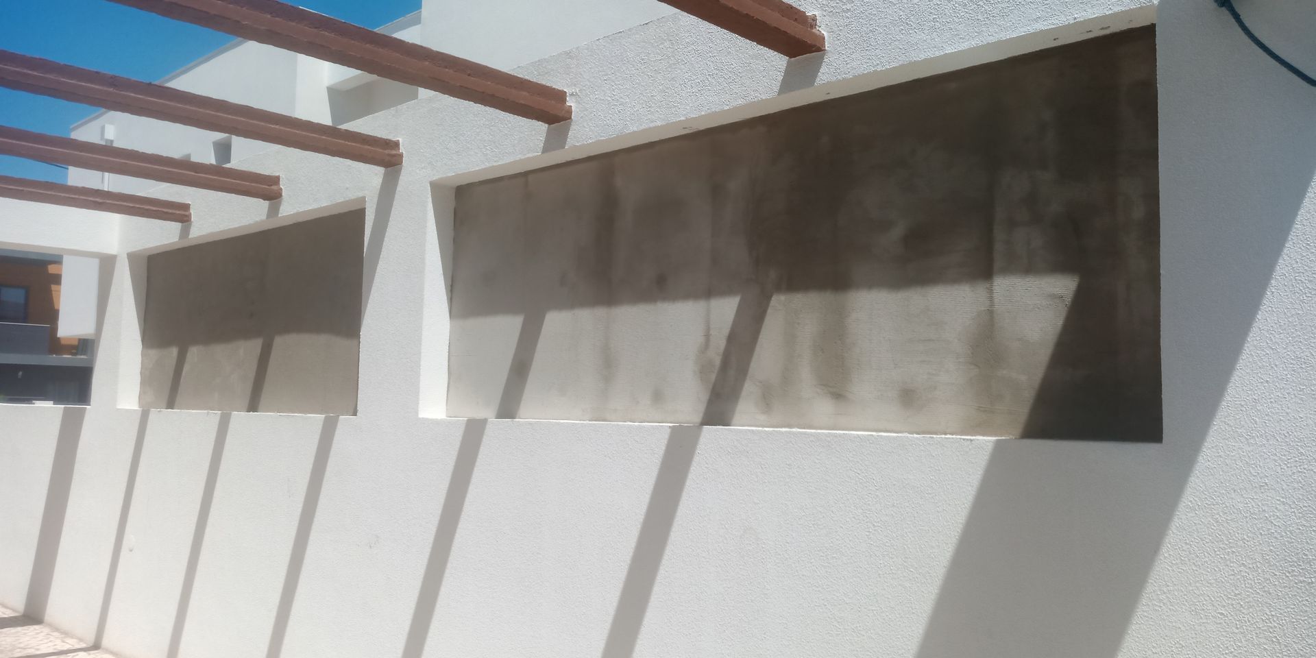 Prédio branco com janelas retangulares abertas; vigas de madeira acima.