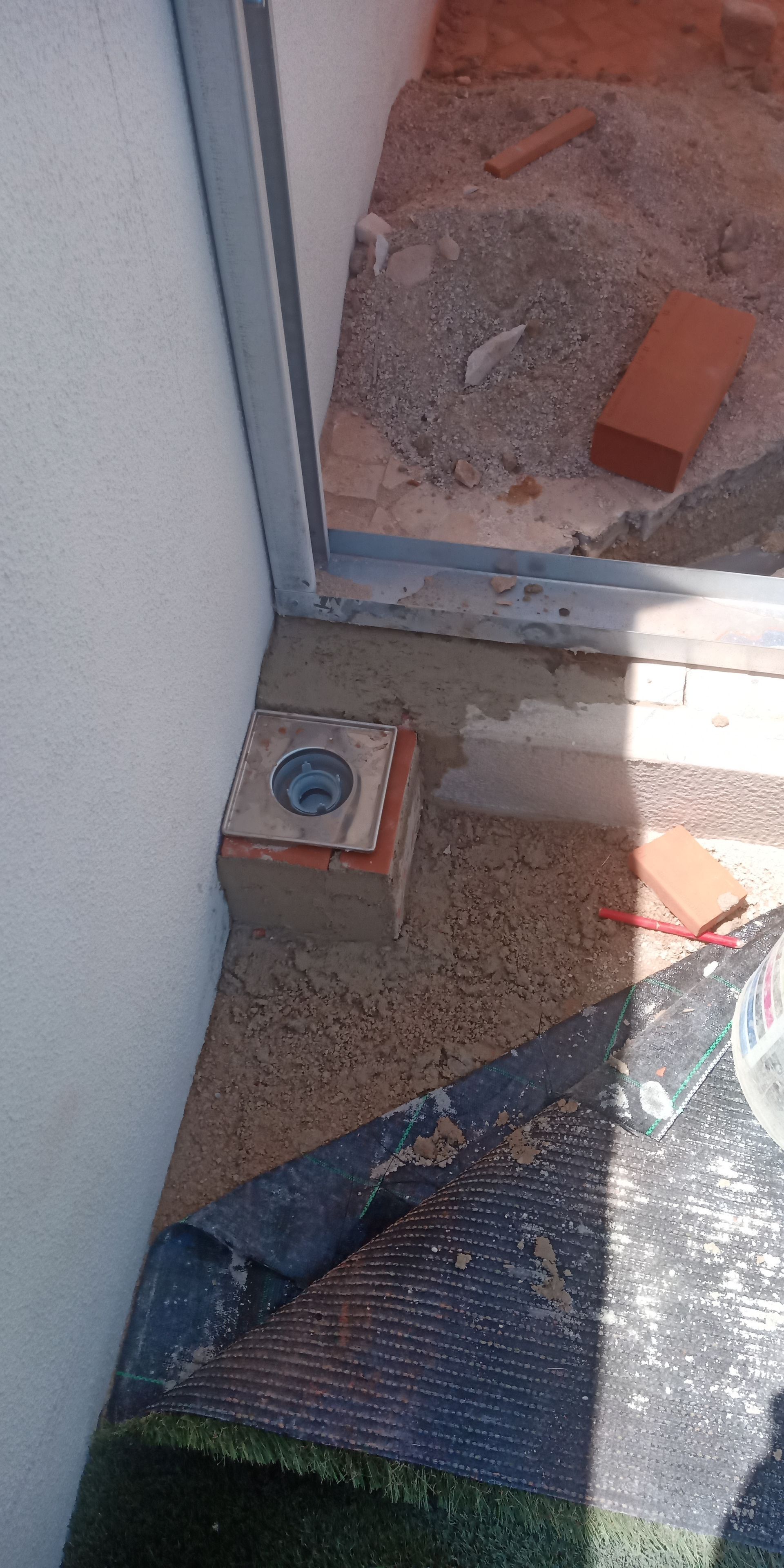 Tijolos e materiais de construção ao lado de uma estrutura metálica.