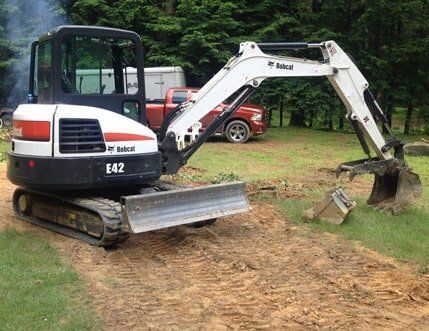 A bobcat excavator is sitting on top of a dirt field.