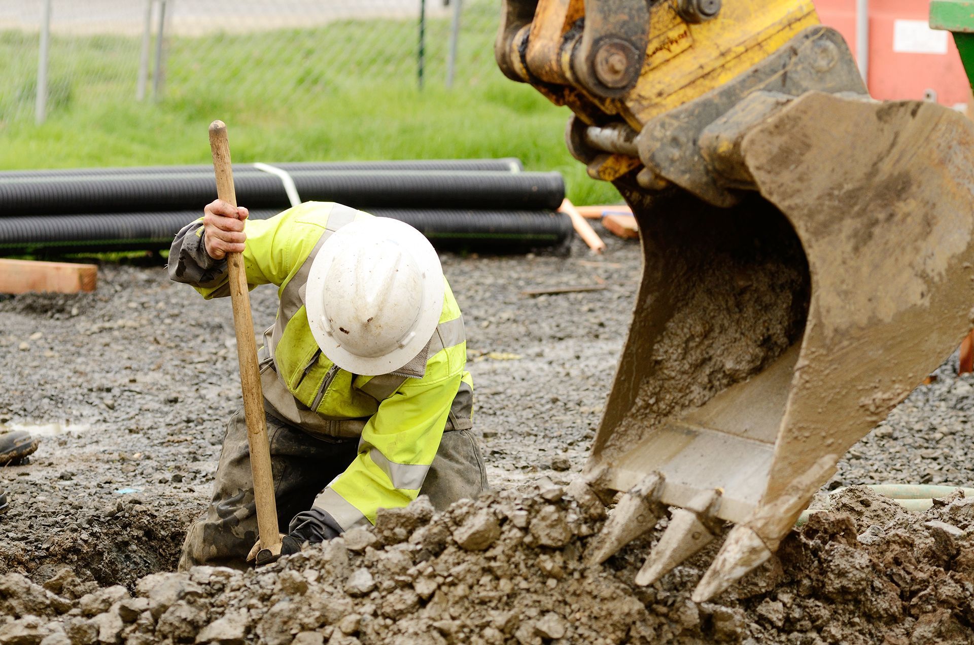 A construction worker is digging a hole in the dirt with a shovel.
