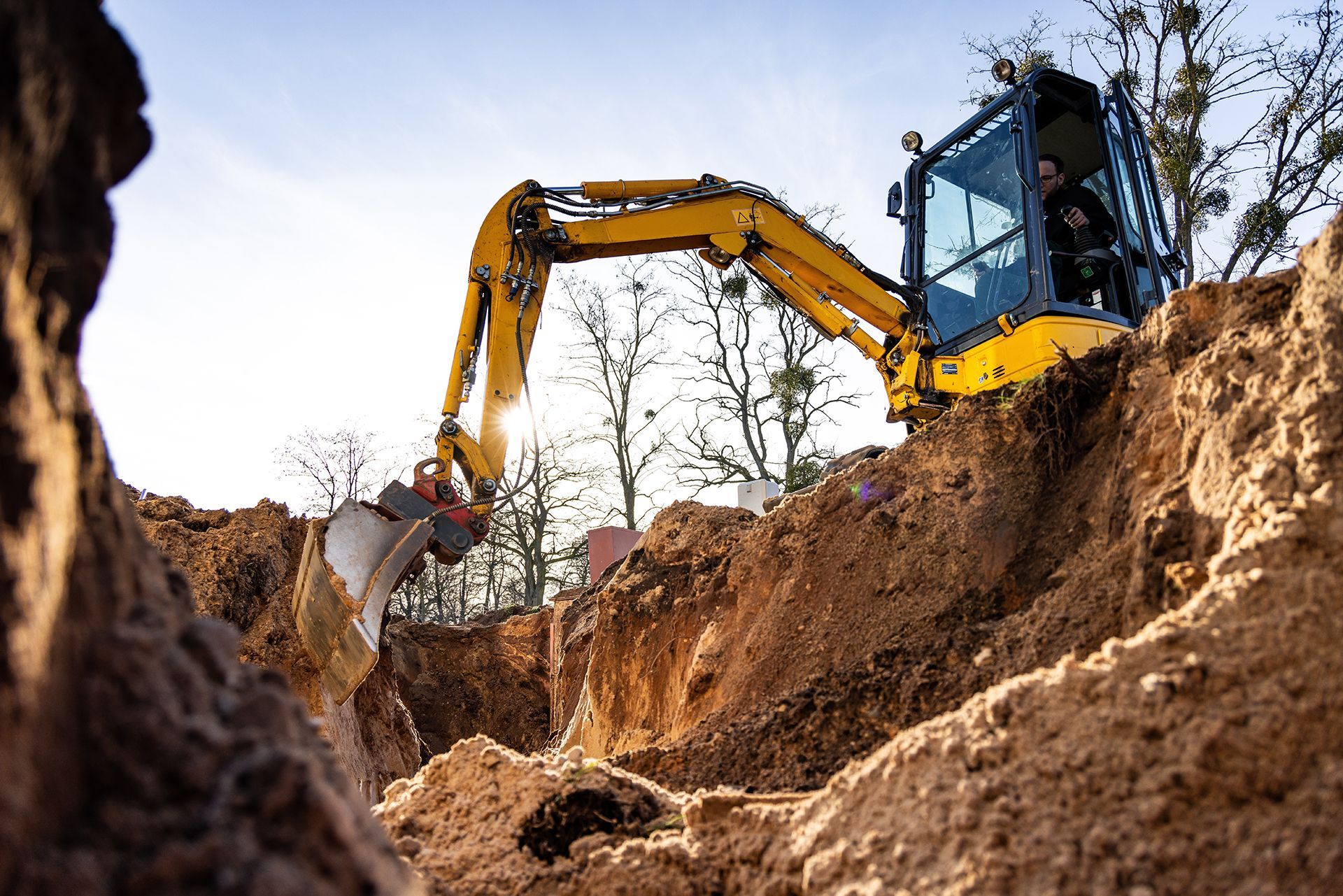 A yellow excavator is digging a hole in the dirt.