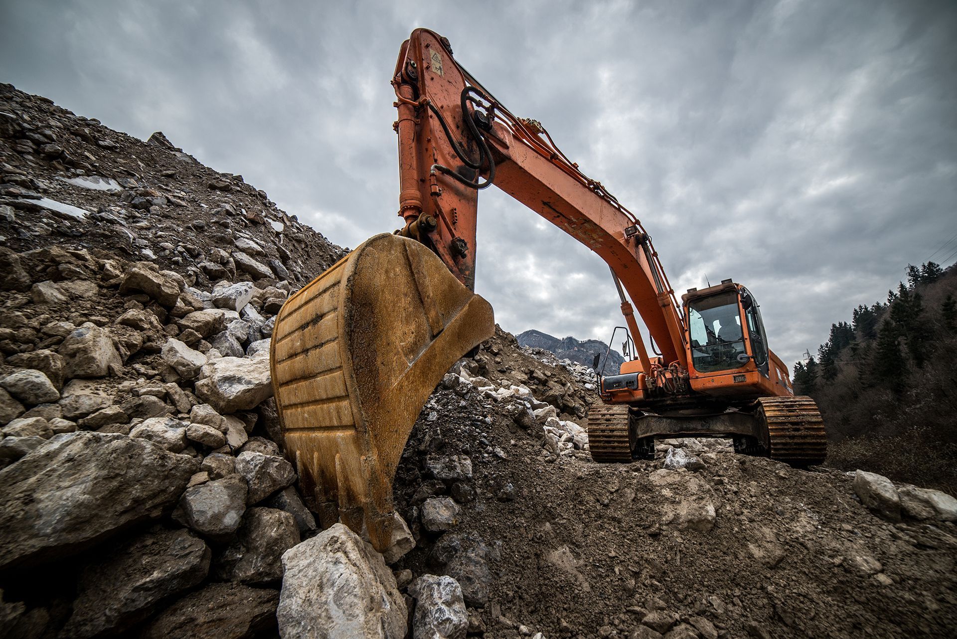 An excavator is moving rocks in a pile of dirt.