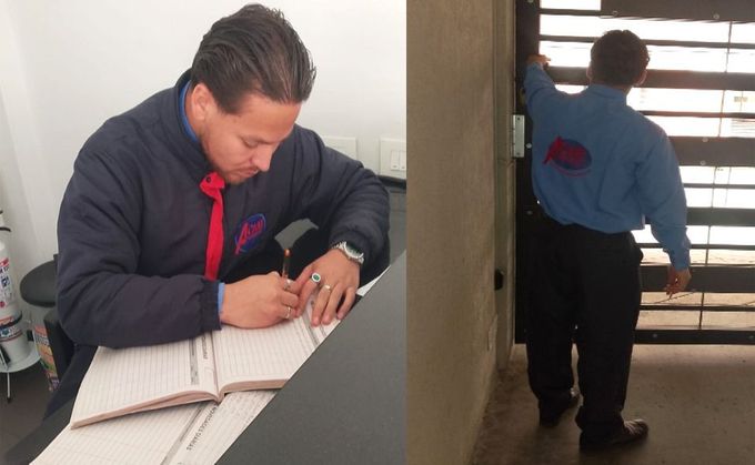 Hombre con chaqueta oscura y corbata roja firmando un cuaderno; otra persona está de pie junto a una ventana.