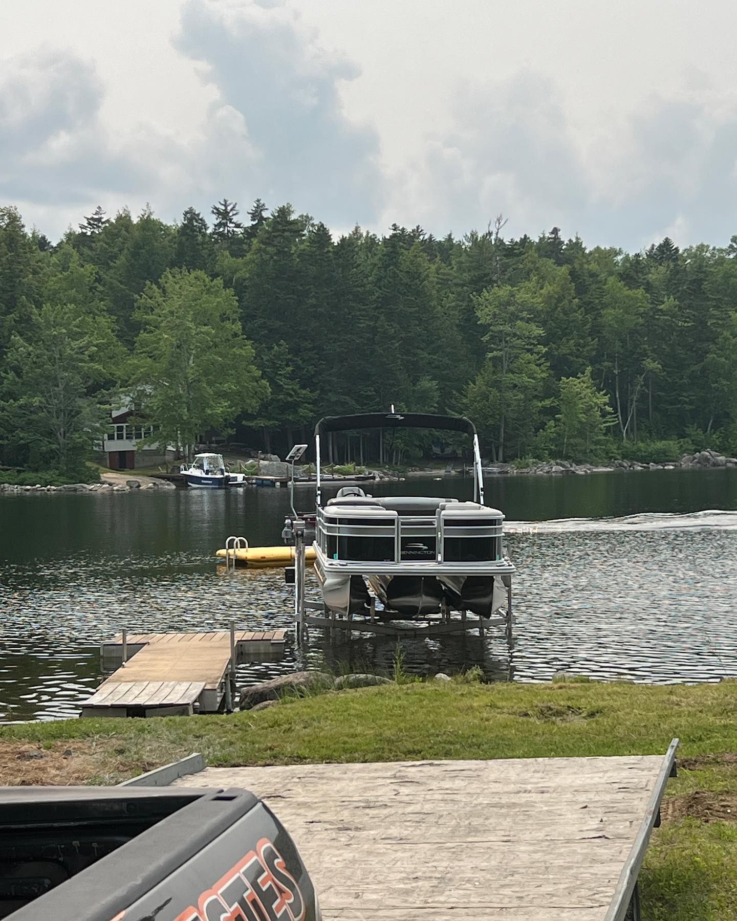 A pontoon boat is docked at a dock on a lake