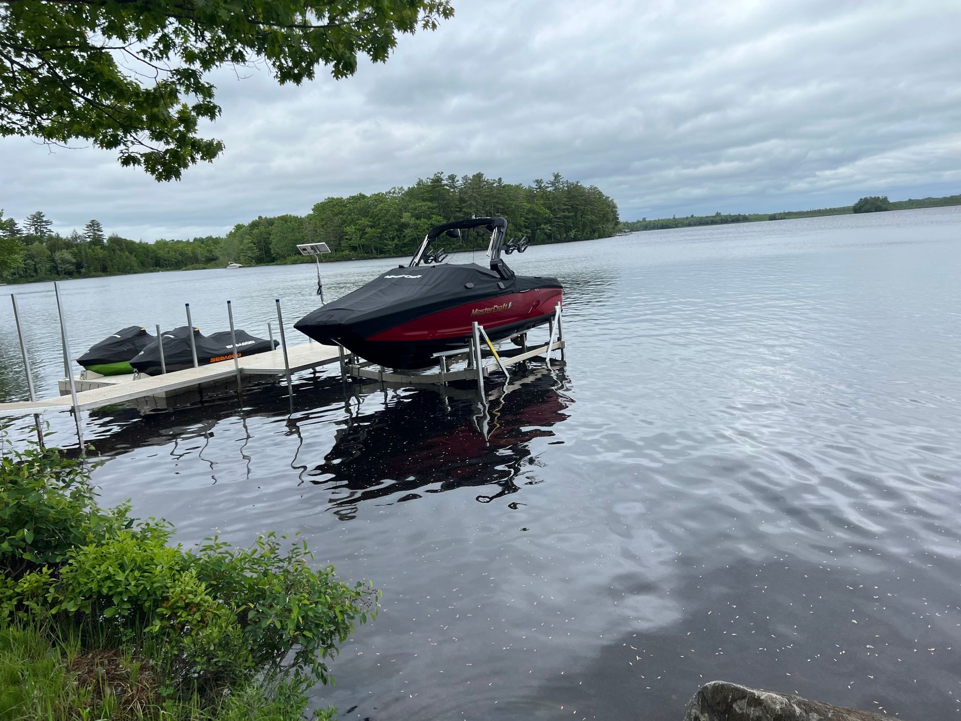 A red boat is docked at a dock on a lake.
