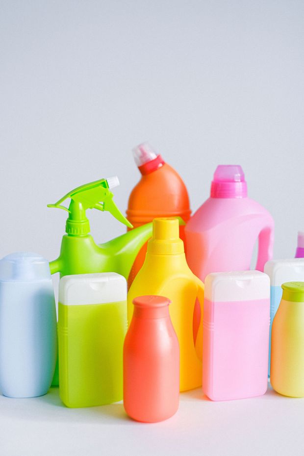 Colorful plastic spray bottles and pump dispensers arranged on a light background.