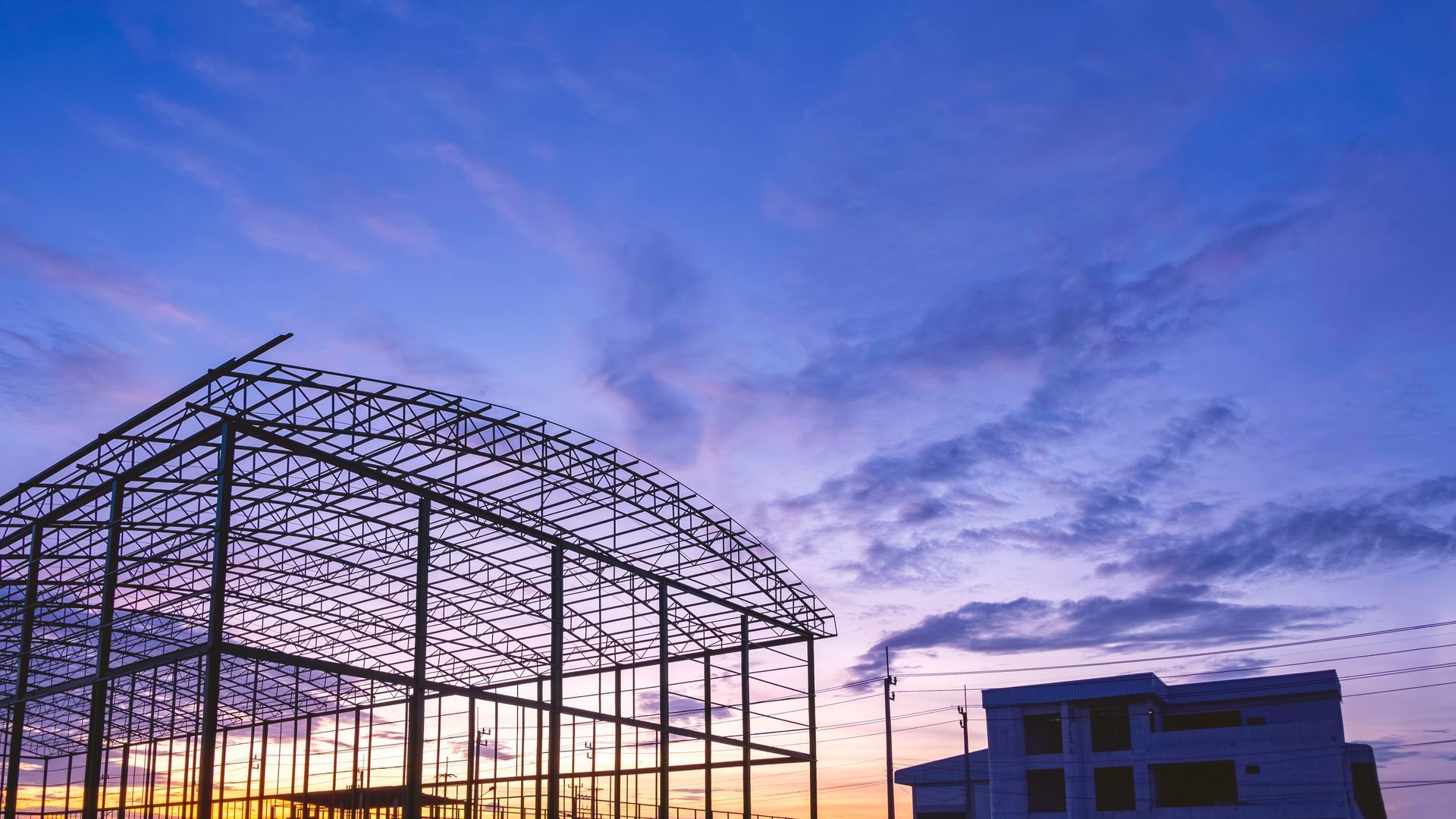 A man is welding a metal structure on top of a building.