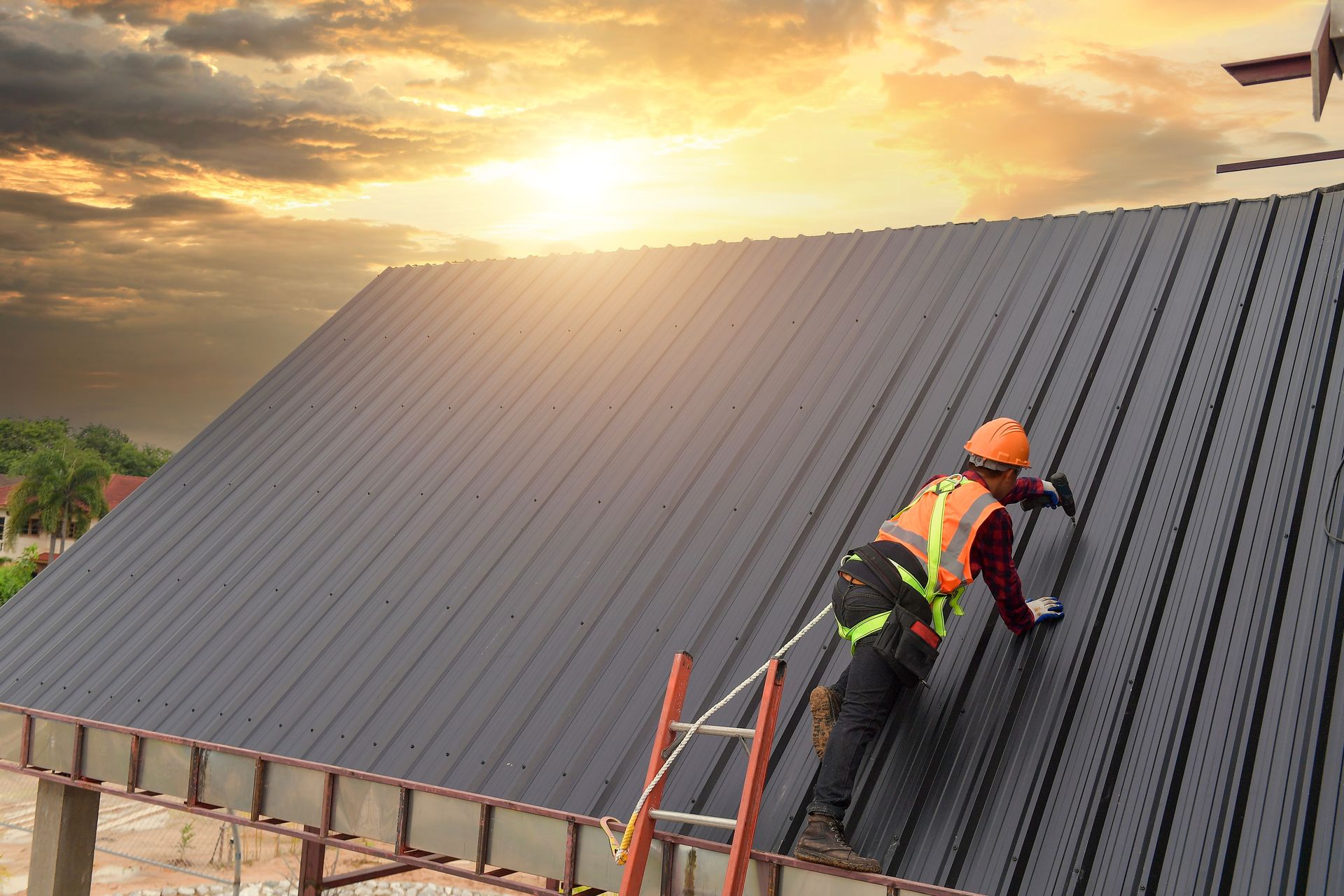 A man is climbing a ladder to install a metal roof.