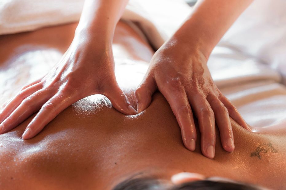 Hands giving a back massage with oil on bare skin