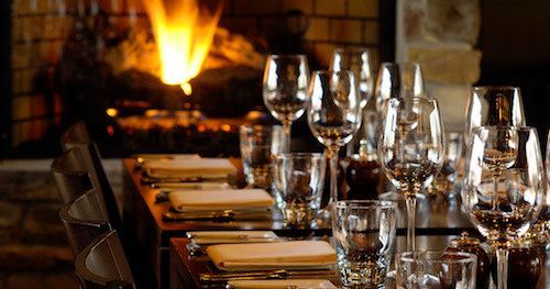 A long table set for a dinner party with a fireplace in the background.