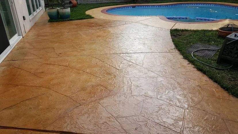 Concrete patio with faux stone pattern and pool in backyard.