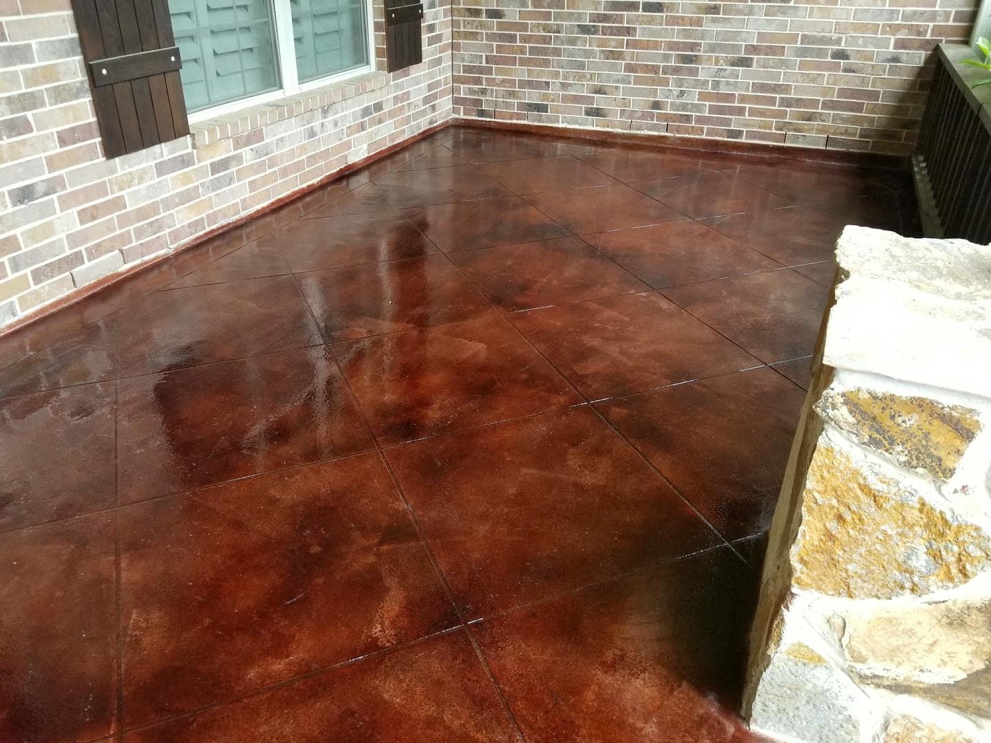Brown stained concrete porch with brick and stone accents.