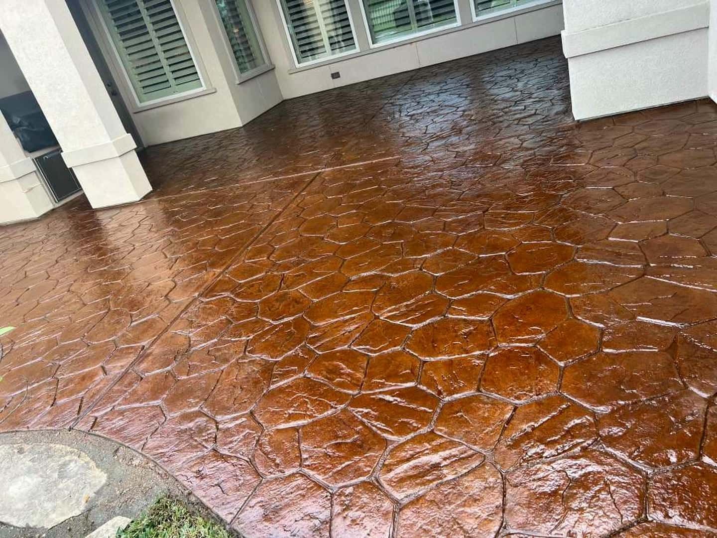 Brown stamped concrete patio with stone pattern, reflecting light.