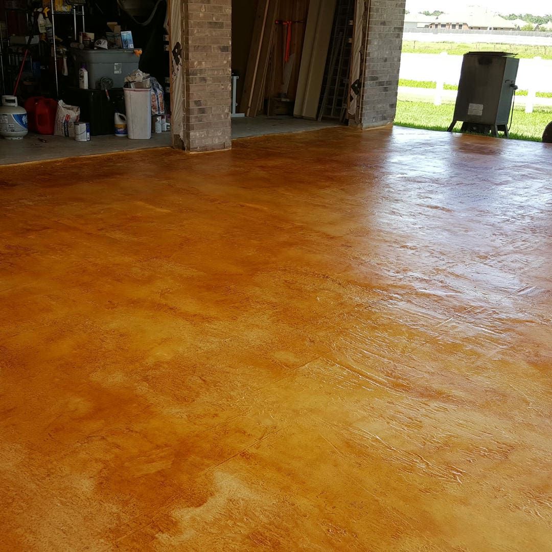 Tan and orange stained concrete floor in a garage, reflecting light.