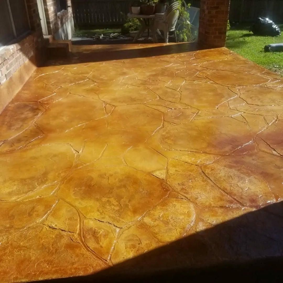 Stamped concrete patio with a natural stone pattern and stained in shades of brown and yellow.