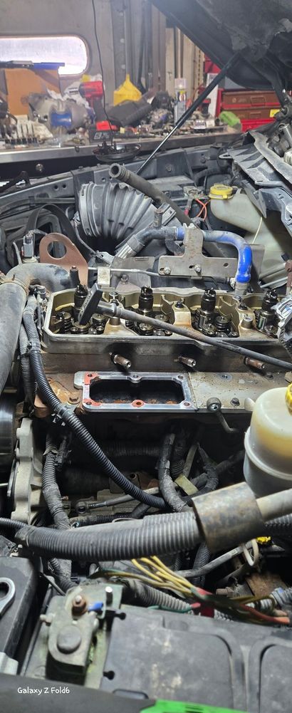 The engine of a red car is visible under the hood.