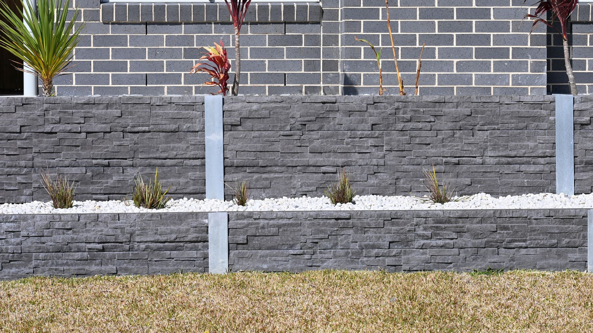A brick wall with planters in front of a house.