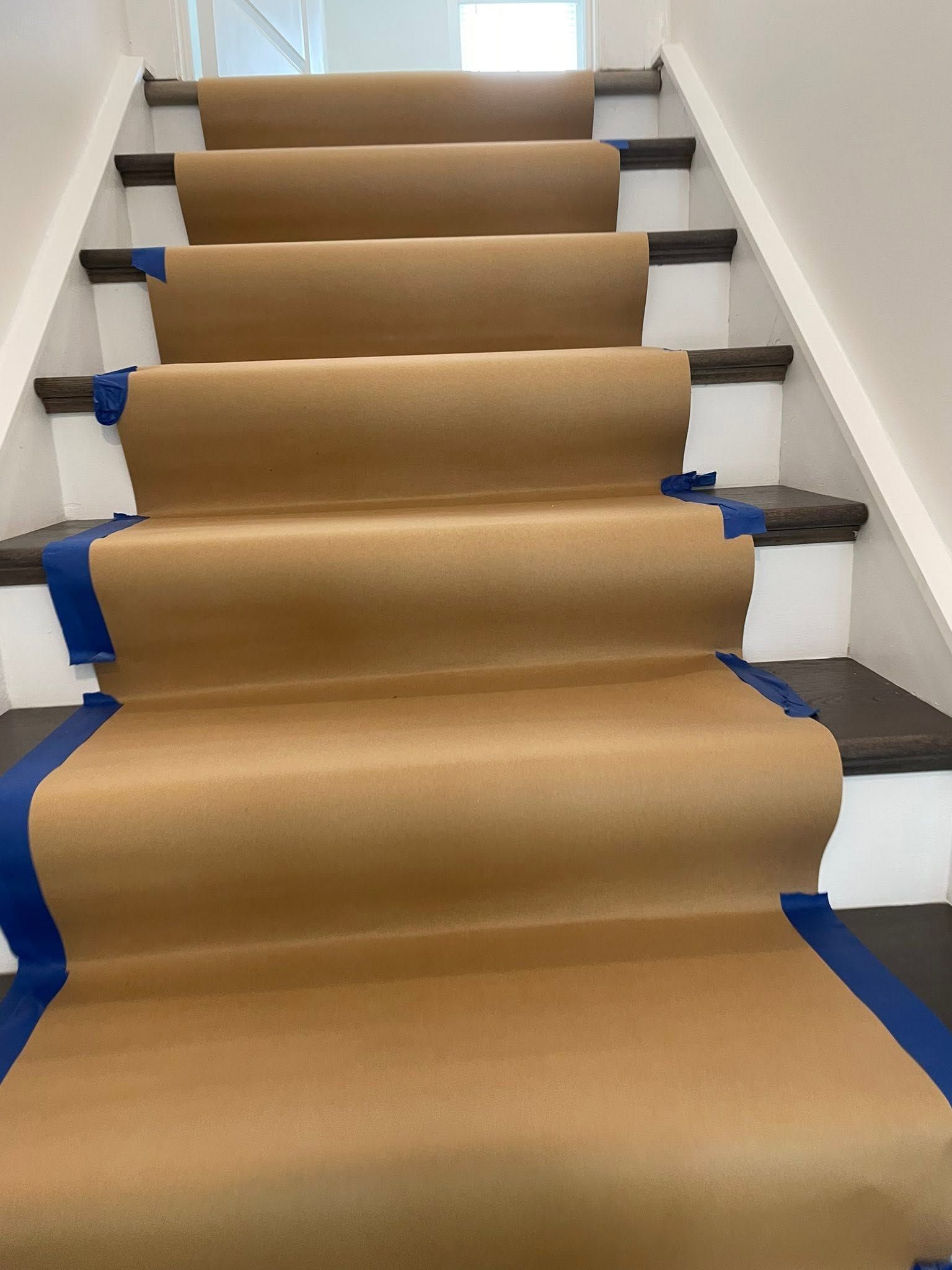Staircase covered in brown paper with blue tape along the edges during renovation