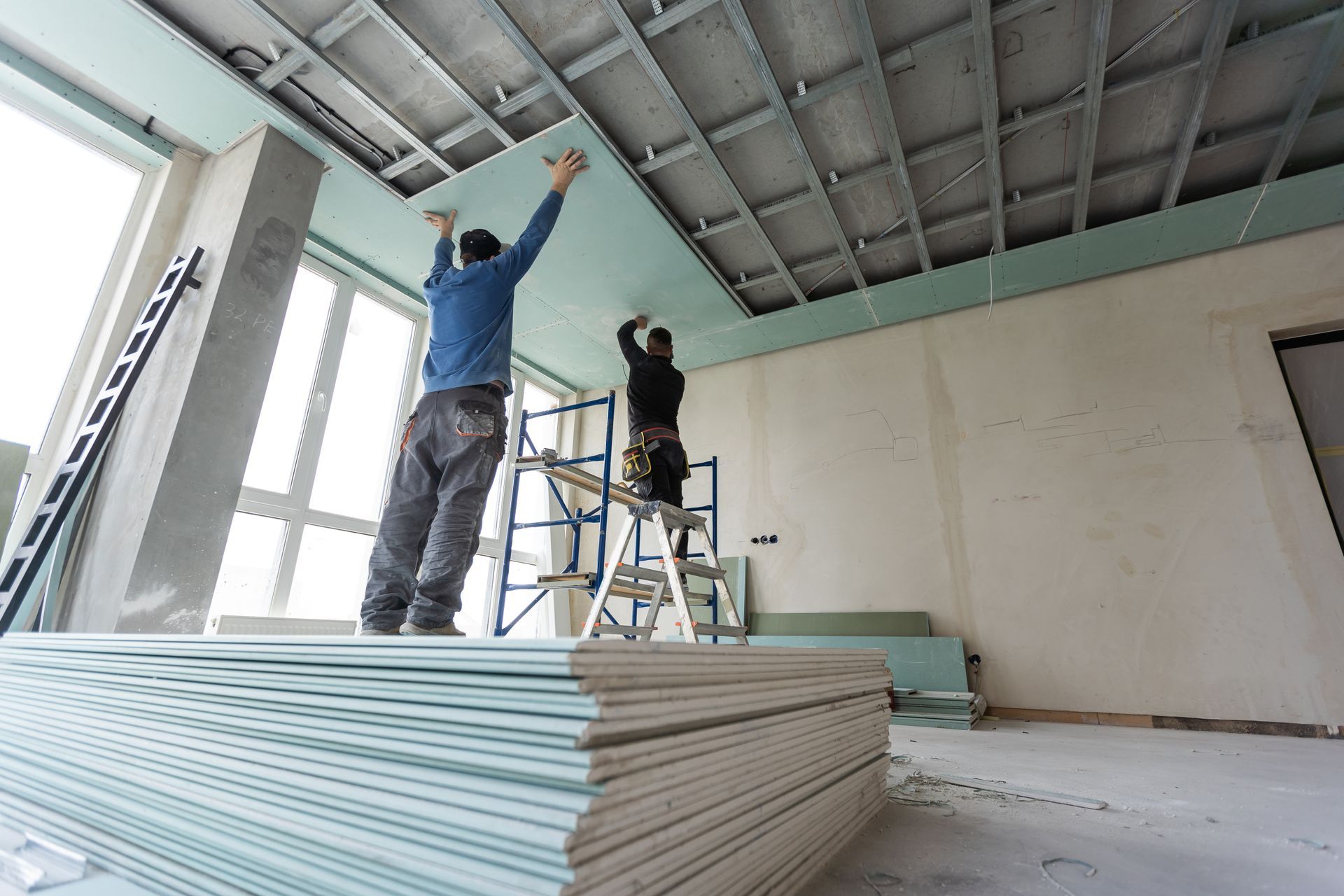 Hand patching a hole in a white wall with spackle and a putty knife.