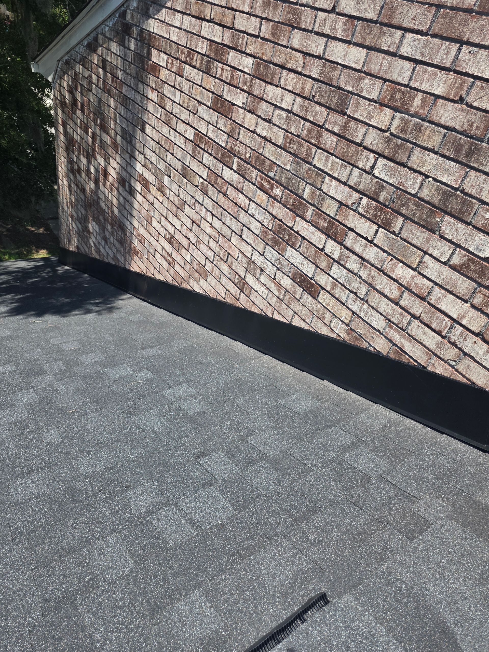 Sunlit brick wall beside a cracked asphalt surface with a long diagonal shadow