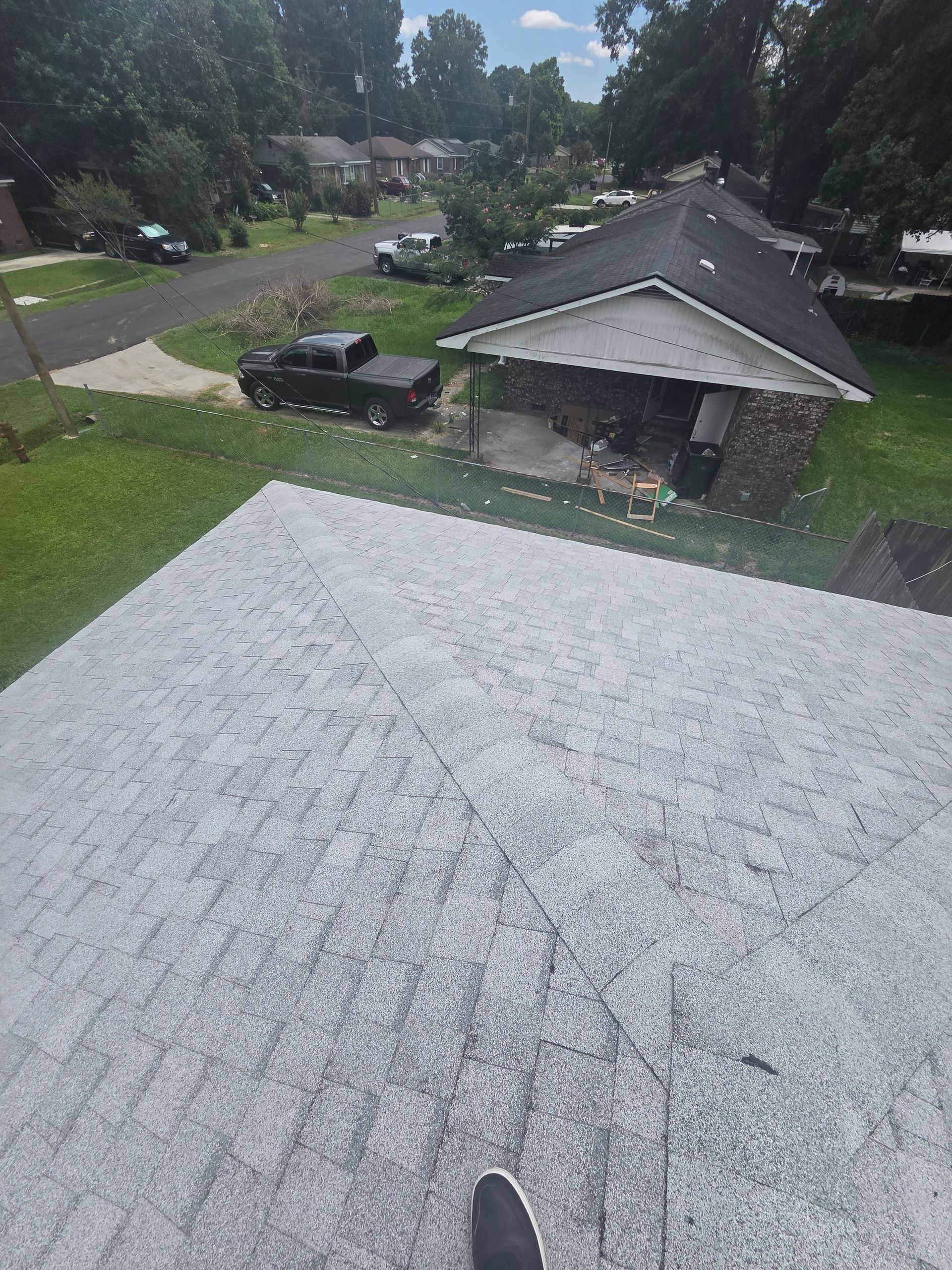 Rain-speckled rooftop view of a suburban street and houses, with a partially visible shoe at the bottom.