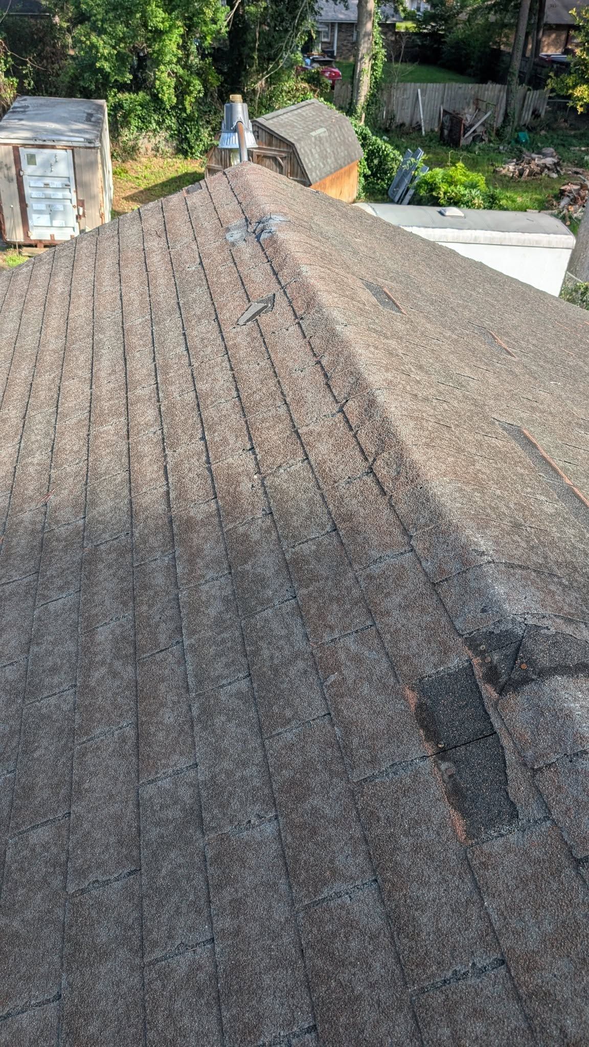 A steep, weathered shingle roof with a small roof vent near the ridge.