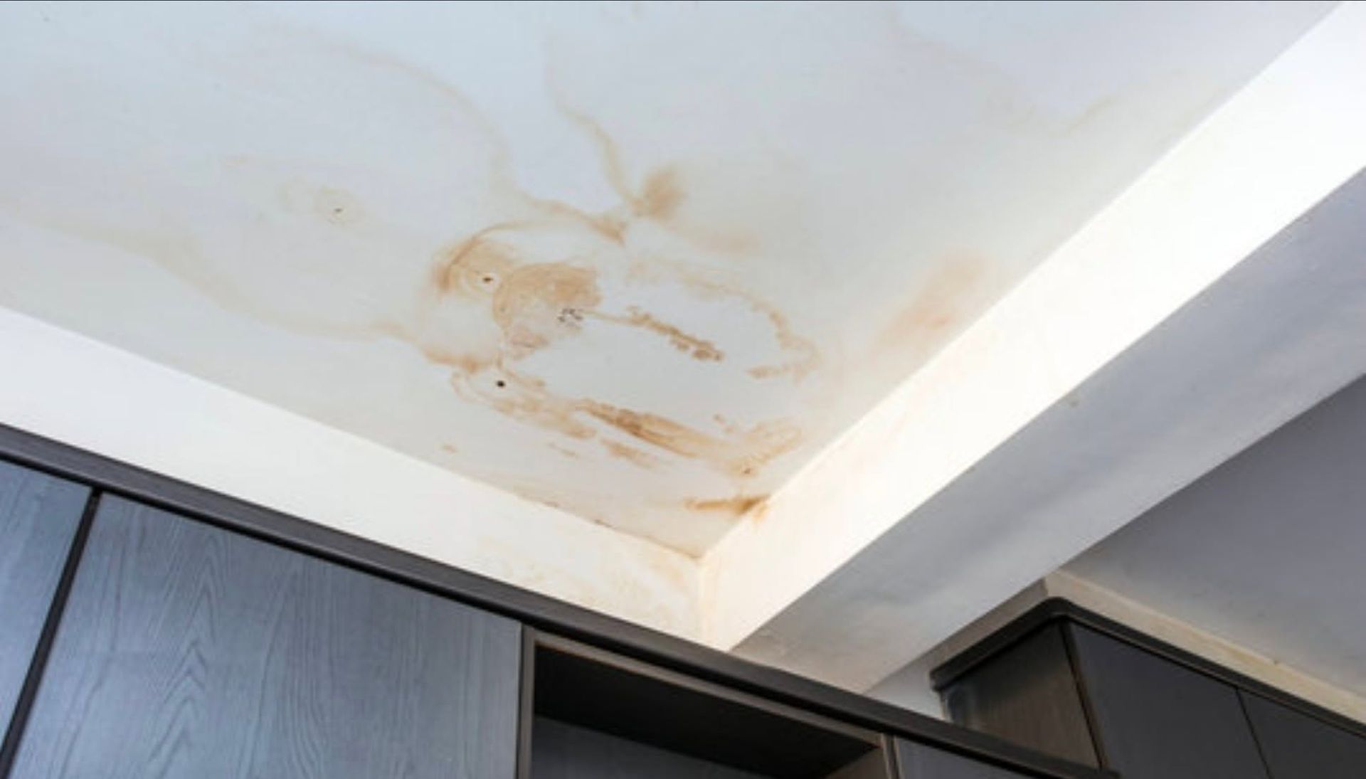 Water-stained ceiling above kitchen cabinets, with brown discoloration from a leak.