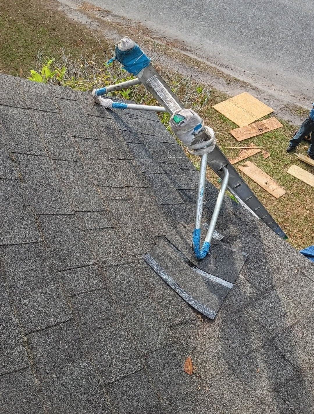 Rooftop solar panel mount with blue components and wires, viewed from above near a roof edge.