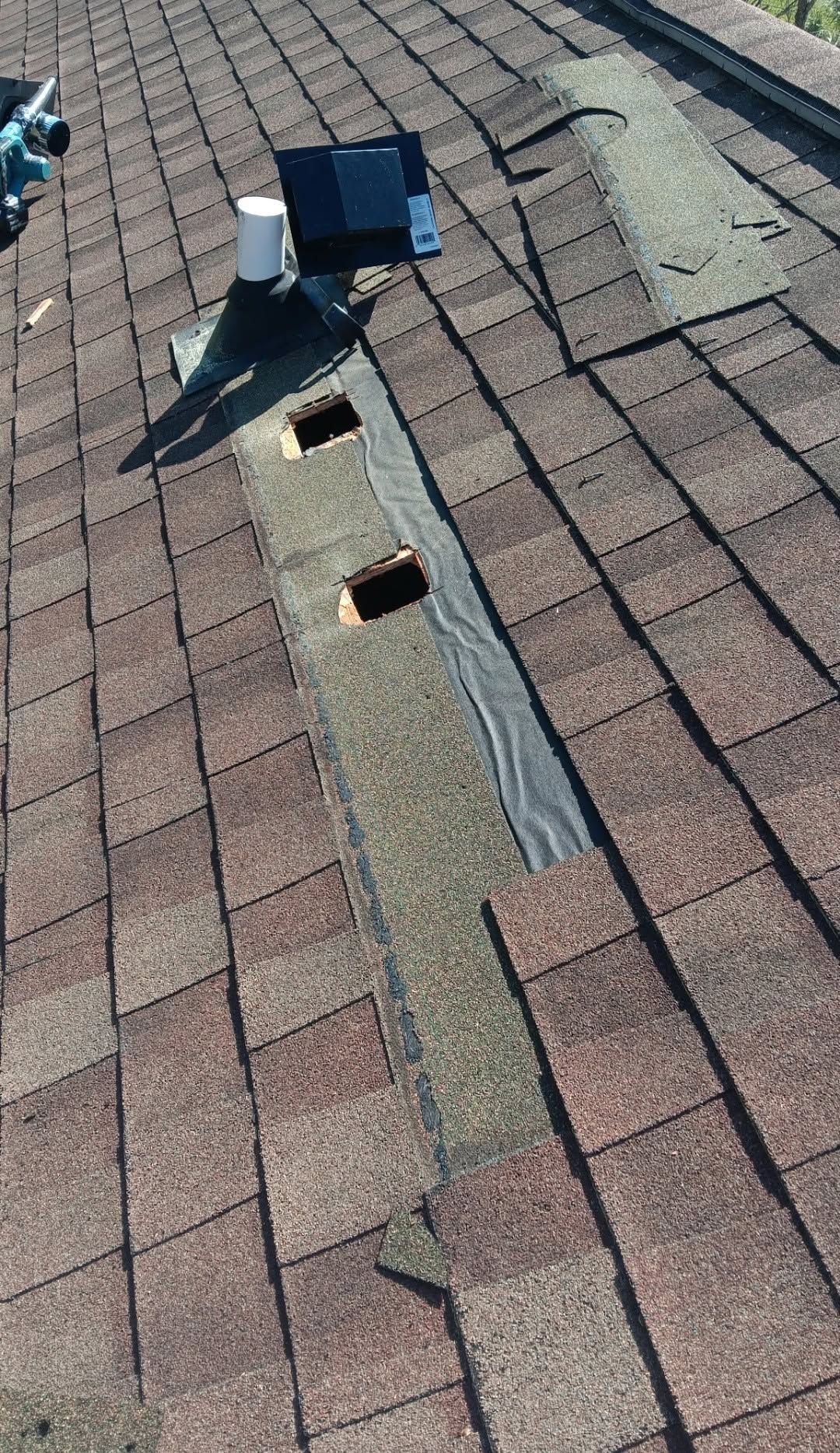 Roof shingles with a long vent pipe and two rectangular roof vents.