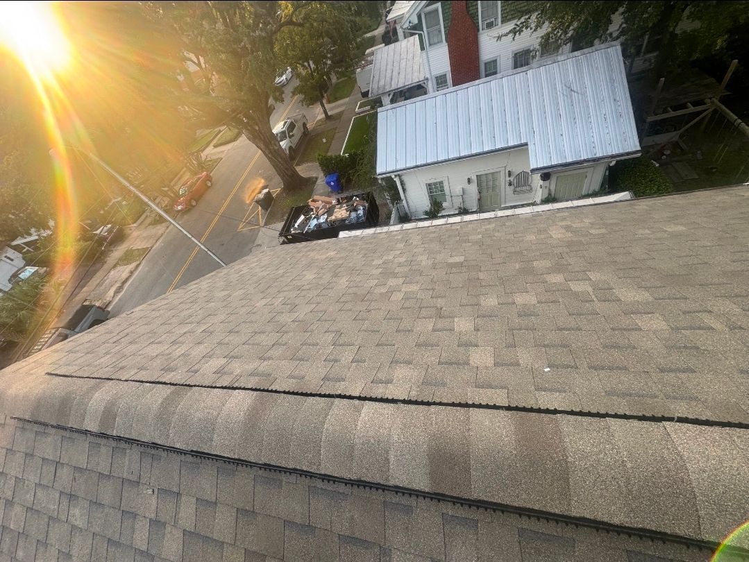 Sunlit sloped rooftop overlooking a street and small house below