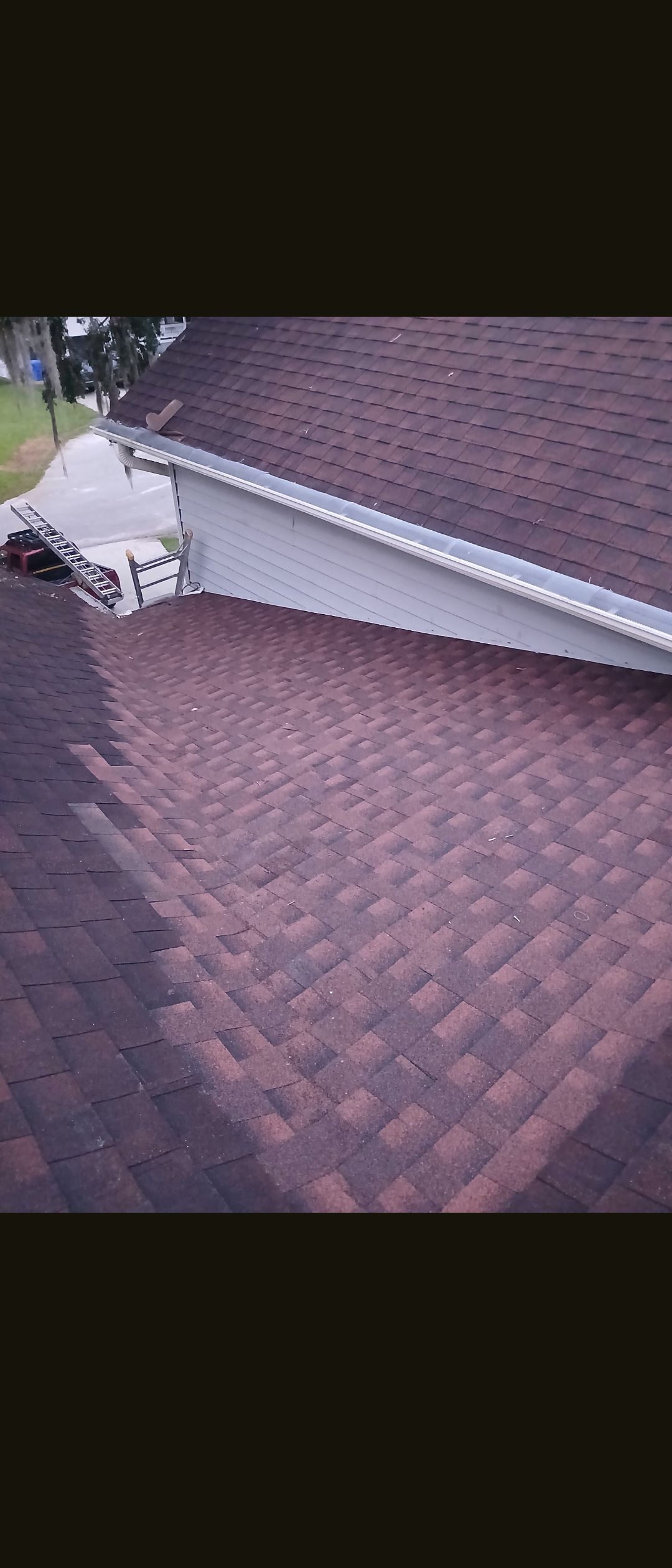 Roof with brown shingles and a white dormer window on a house.