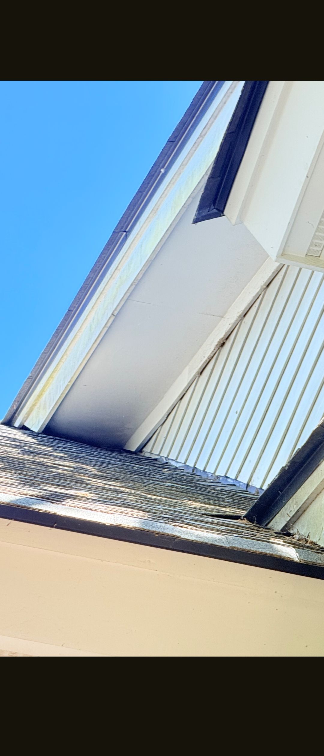 Upward view of a white building facade against a bright blue sky