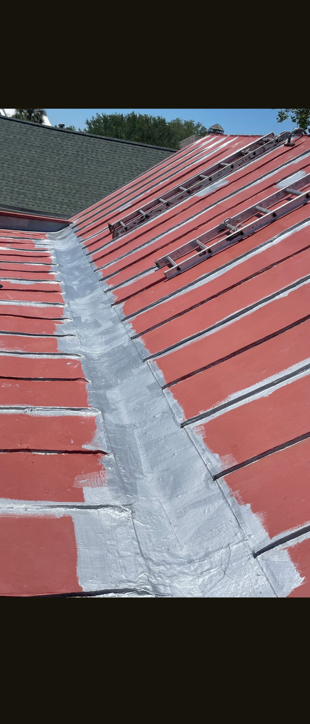 Red tiled roof with a gray mortar ridge seam running up the center under a blue sky