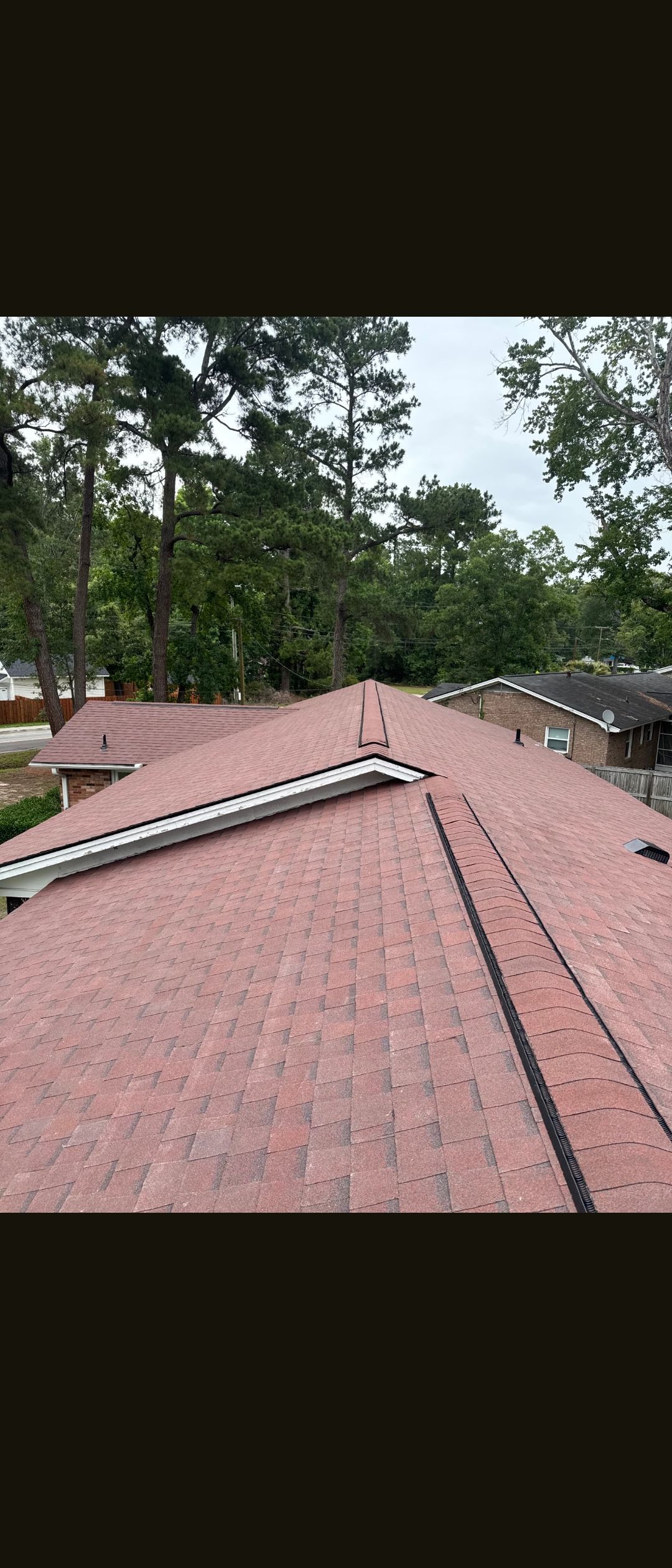 Red-tiled roof with gutters overlooking trees and cloudy sky