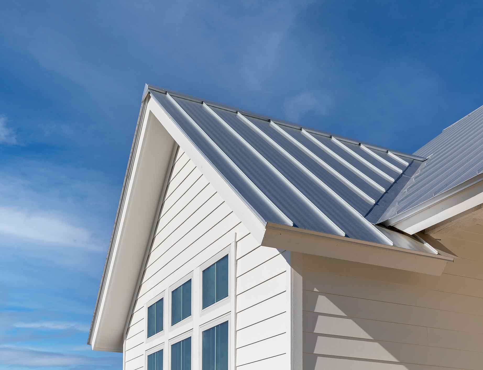 White house with a metal roof against a bright blue sky.