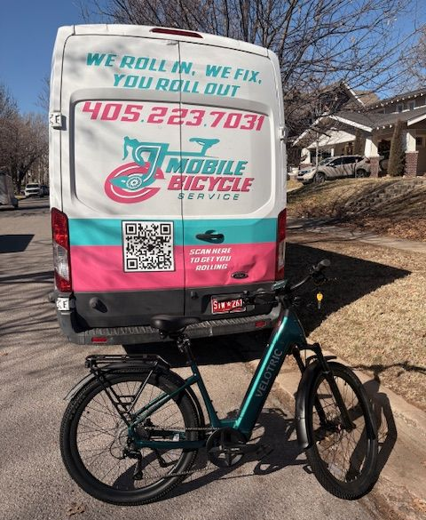 White van with pink bicycle service logo, parked on a street.