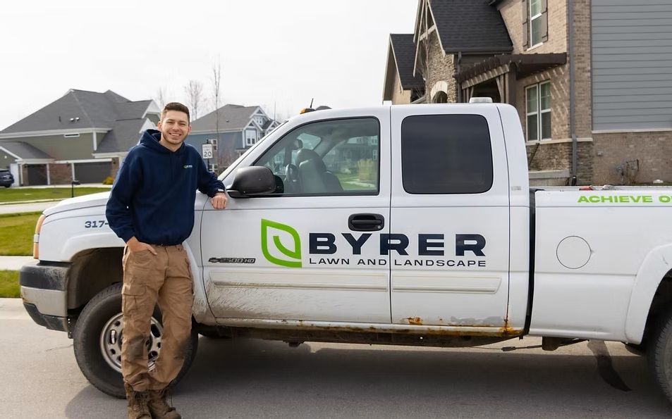 Man standing beside a white Byrer service truck in a residential driveway