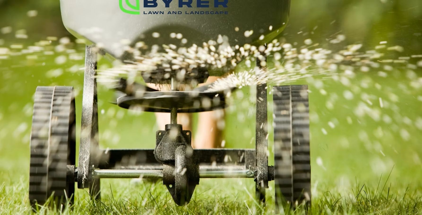 Sprinkler system spraying water in a grassy field, with a BYREN machine in the background
