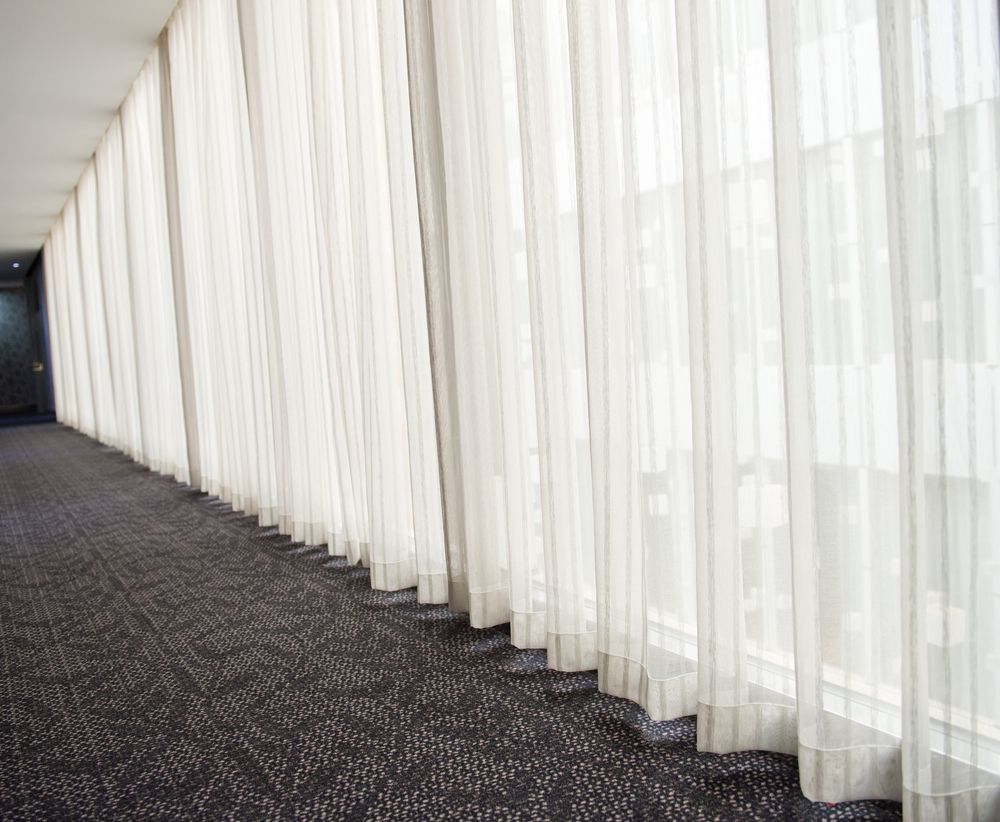 A Long Hallway With White Curtains And A Carpet — Pinnacle Carpet & Upholstery Cleaning In Wyong, NSW