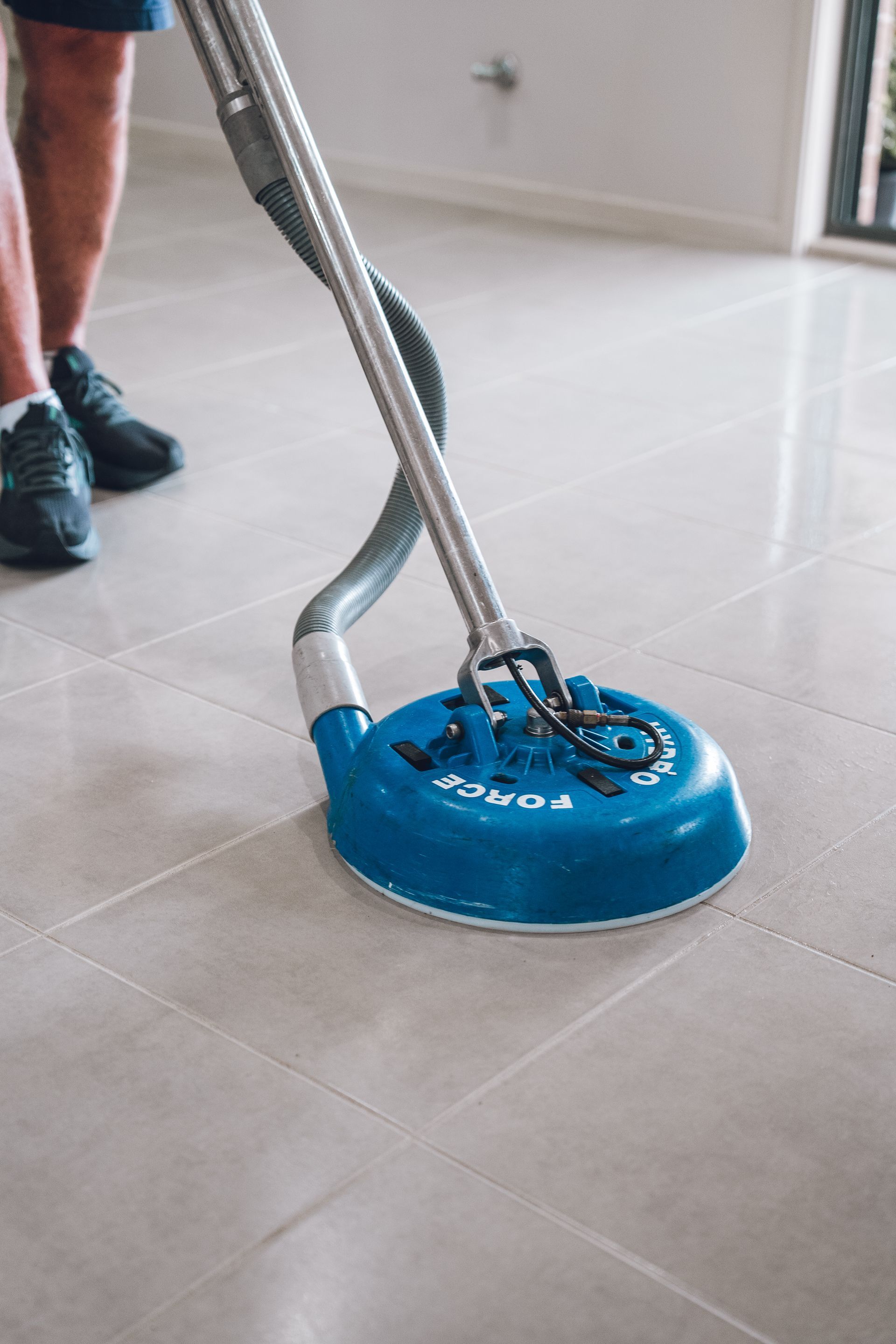 A person is cleaning a tiled floor with a vacuum cleaner. — Pinnacle Carpet & Upholstery Cleaning In Hunter Valley, NSW