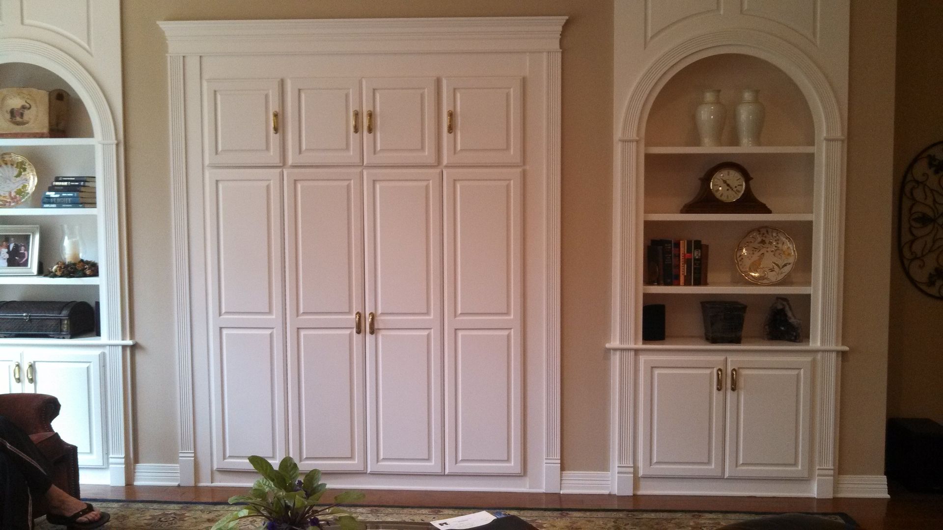 Built-in white cabinets and arched shelving in a living room, with framed art and decorative objects