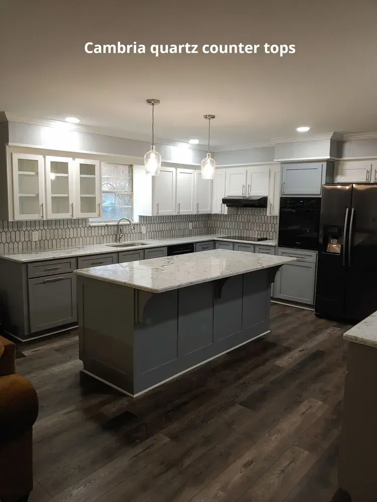 Modern kitchen with gray cabinets, Cambria quartz countertops, dark flooring, and island under pendant lights