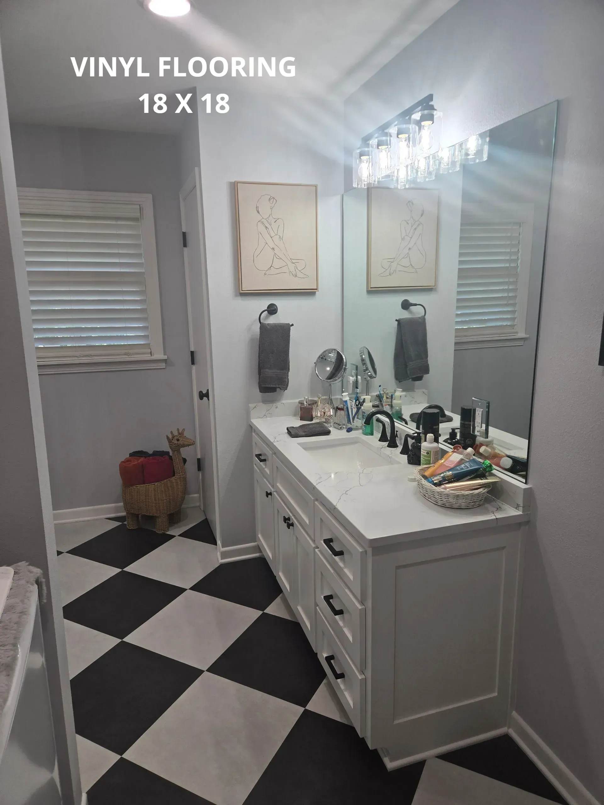 Bathroom with black-and-white vinyl flooring, white vanity, mirrors, and wall art.