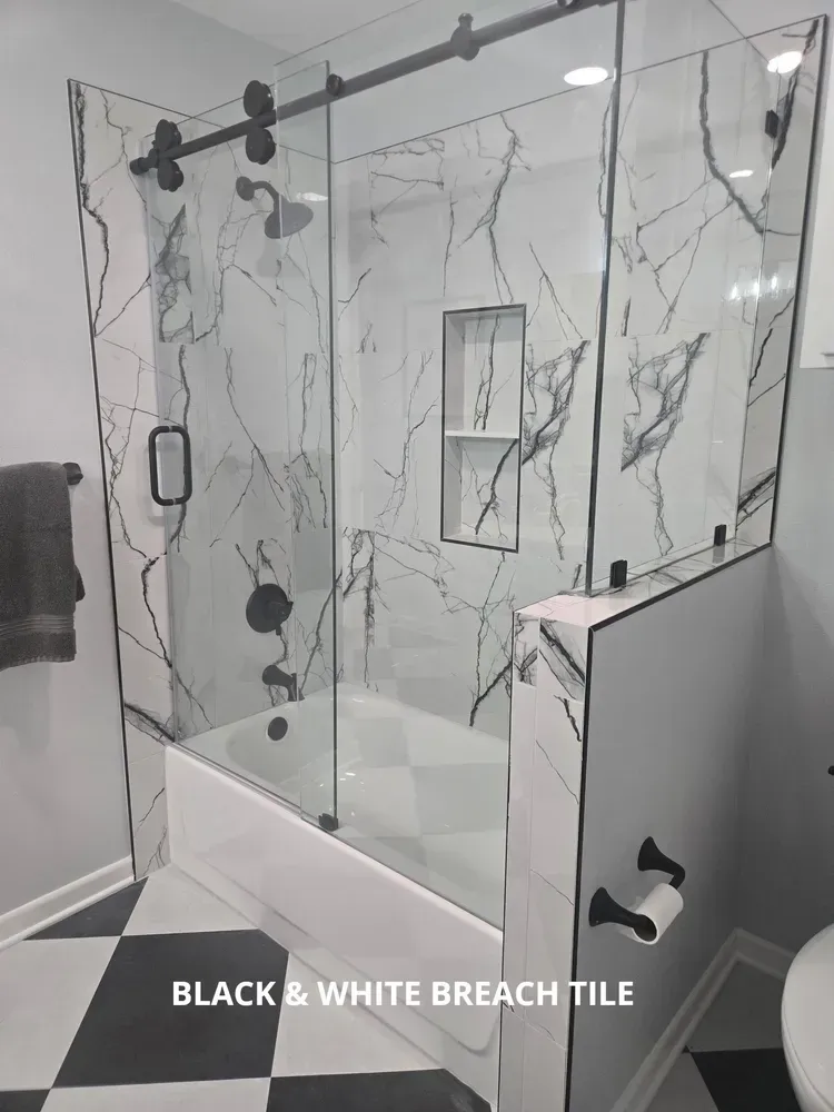Black-and-white marble tile shower with glass doors and black hardware
