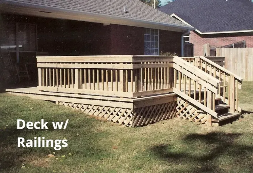 Wooden deck with railings and stairs attached to a brick house in a backyard