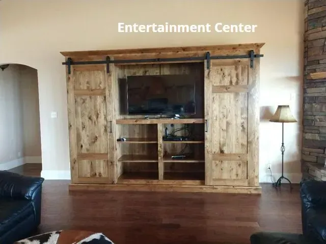 Rustic wooden entertainment center with TV in a living room, flanked by lamps and sofas.